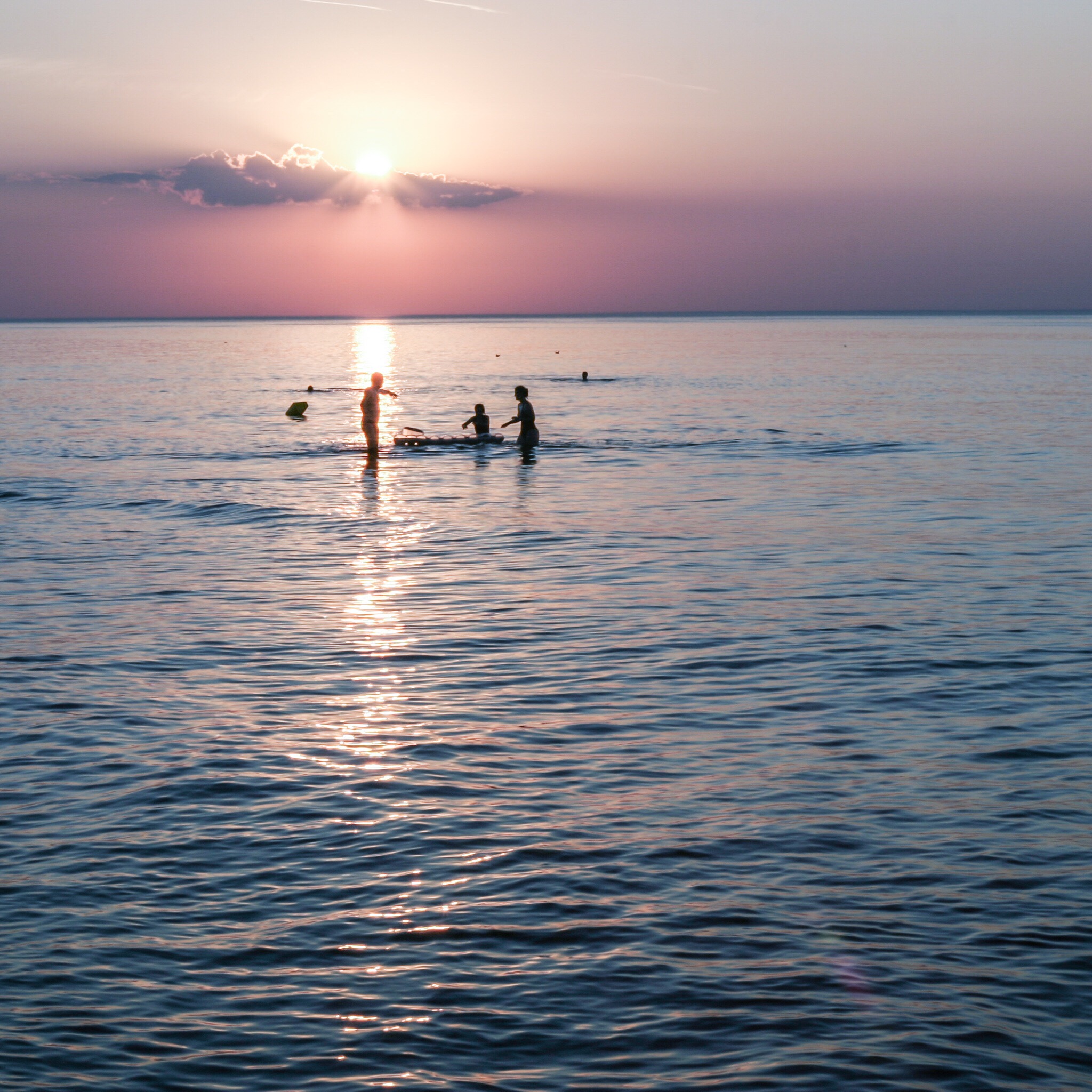 Kids playing in a sea at sunset